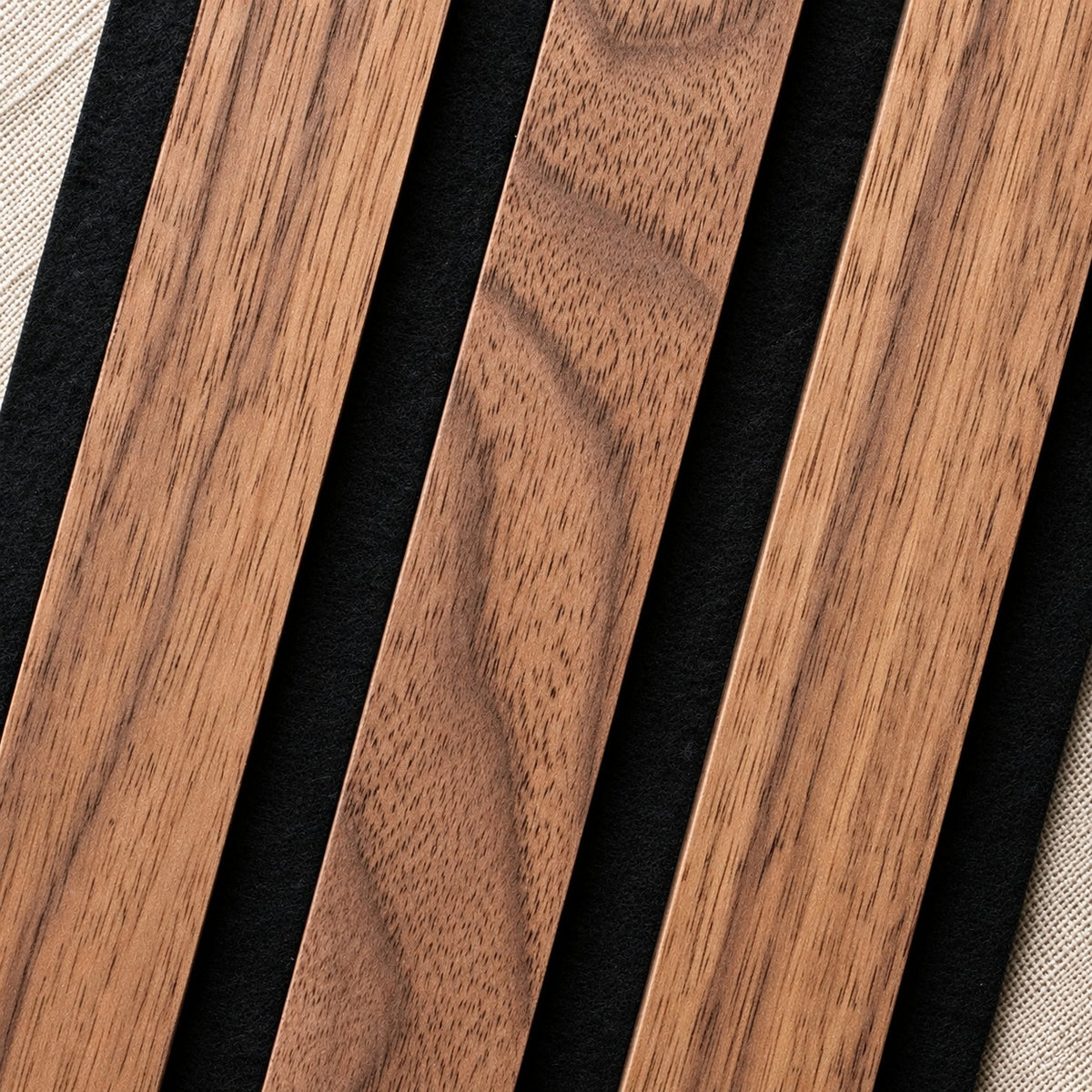 Close-up of TrueWood Lite American Walnut slats on black felt, showing the real walnut veneer grain
